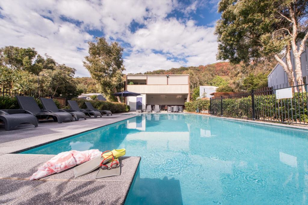 a swimming pool with chaise lounge chairs next to a house at Allure Stradbroke Resort in Point Lookout