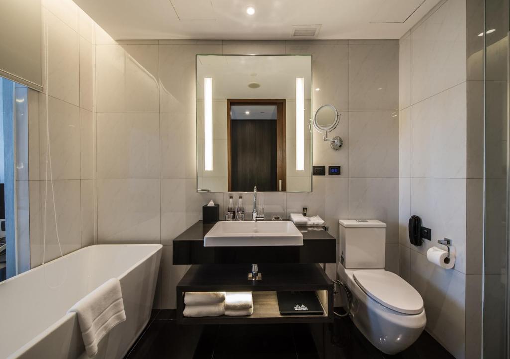 a bathroom with a tub and a sink and a toilet at Amara Bangkok Hotel in Bangkok