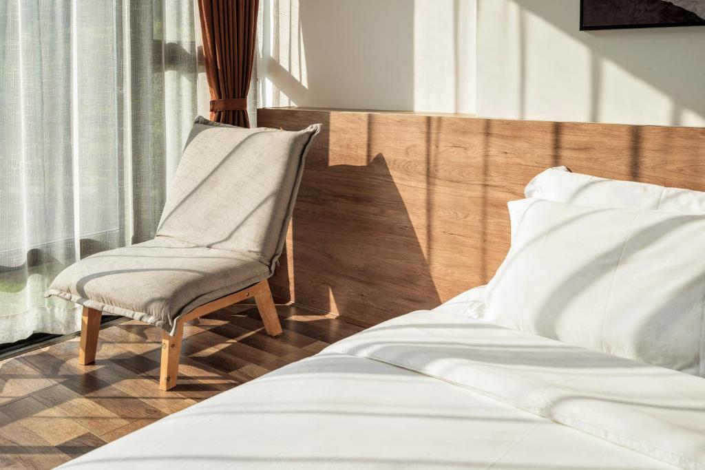 a bedroom with a chair next to a bed at Whispering Mountains Boutique Hotel in Zhangjiajie
