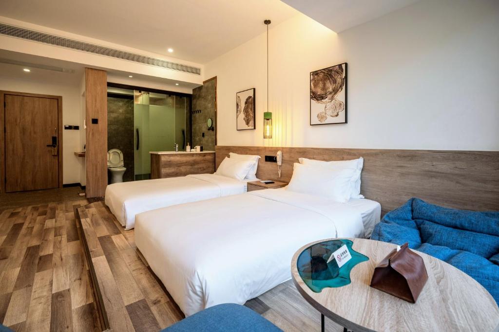 a hotel room with two beds and a blue couch at Whispering Mountains Boutique Hotel in Zhangjiajie