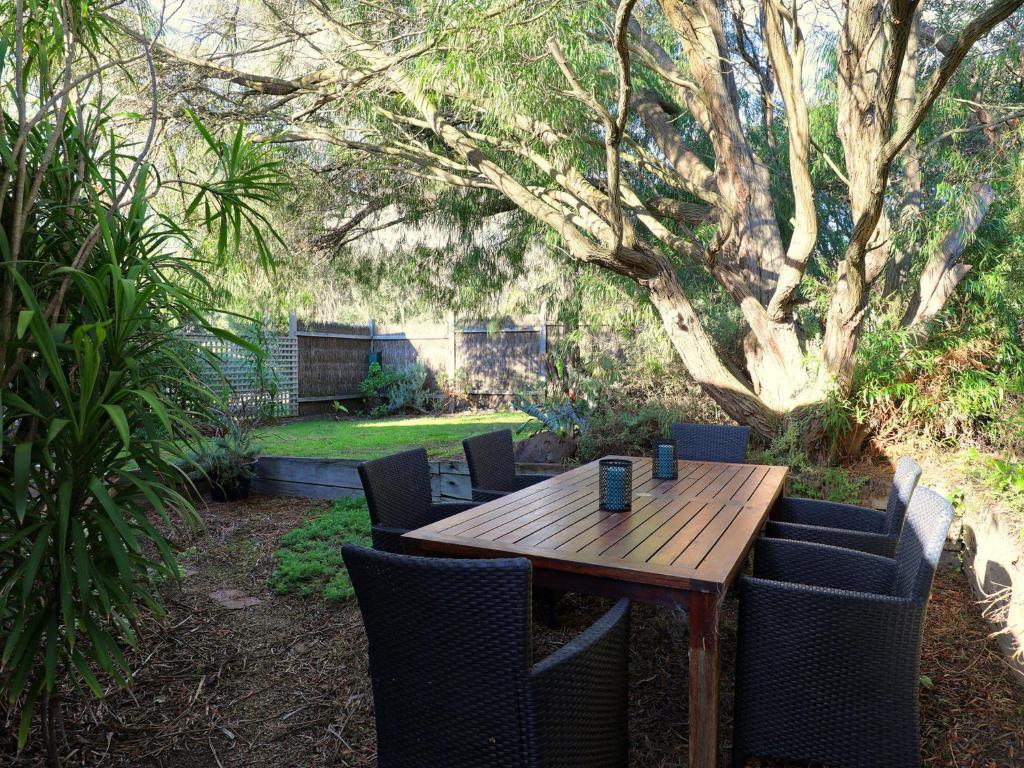 a wooden table and chairs in a yard with a tree at Back Beach Hideaway in Blairgowrie
