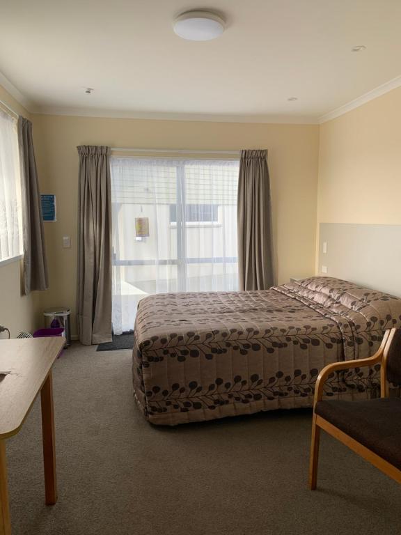 a bedroom with a bed and a large window at Kingswood Motel in Waimate