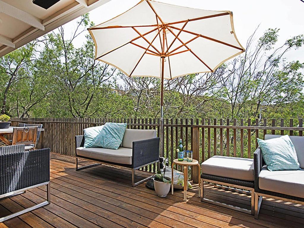 a patio with two chairs and an umbrella on a deck at Treetops in Sorrento
