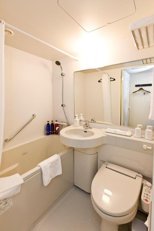 a bathroom with a toilet and a sink and a tub at Sotetsu Fresa Inn Tokyo-Toyocho in Tokyo