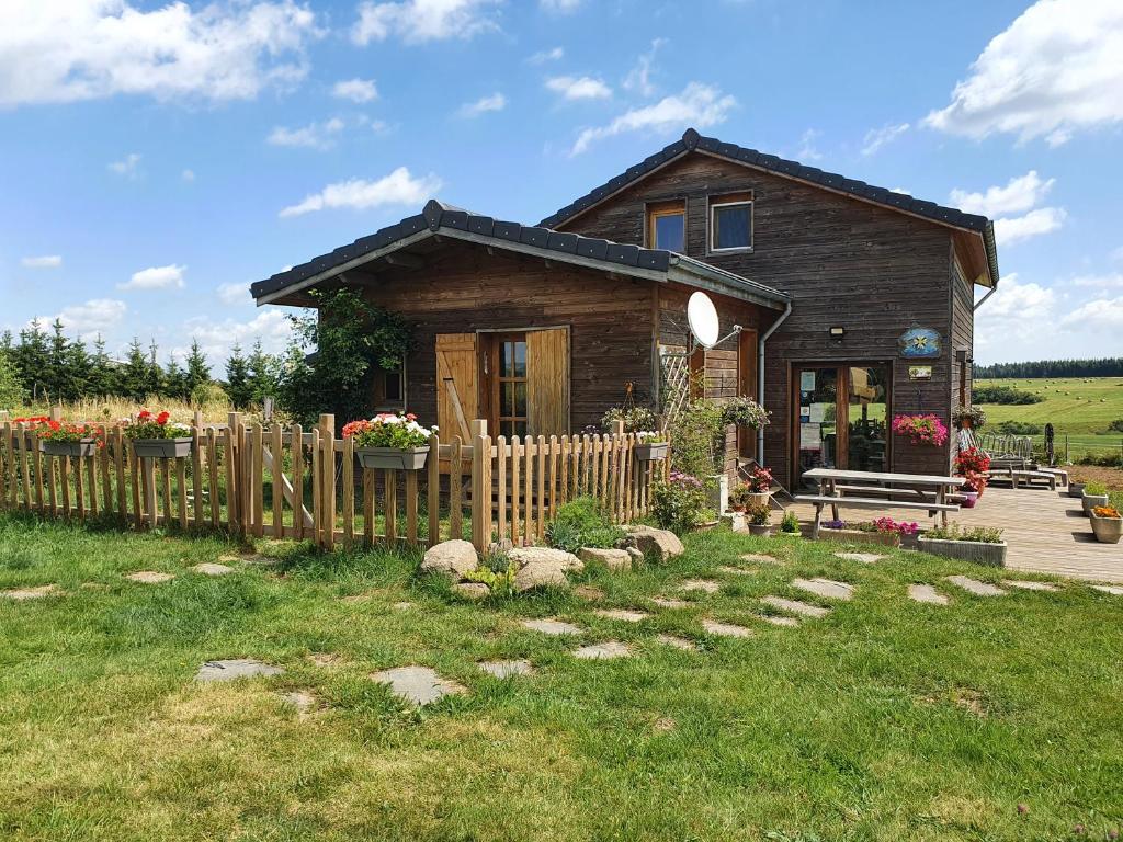 una pequeña casa de madera con una valla y un patio en La Rose des Vents, en Les Vastres