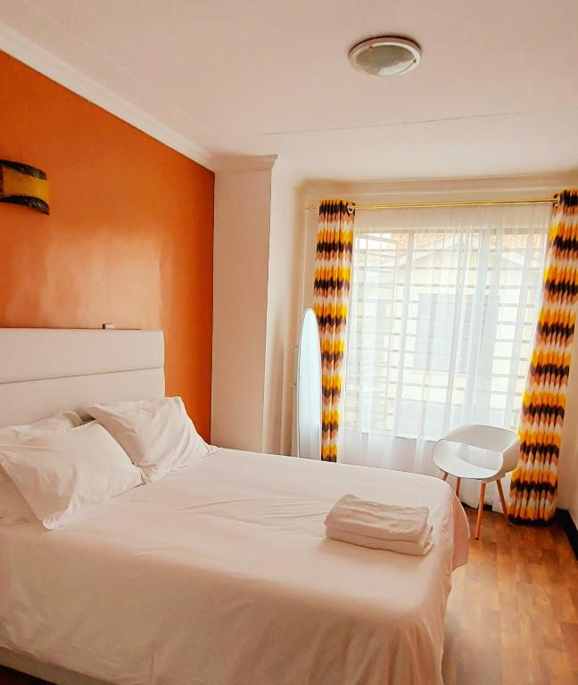 a bedroom with a white bed and a window at Pleasant Nest Homestay near JKIA Airport and SGR Station Nairobi in Nairobi