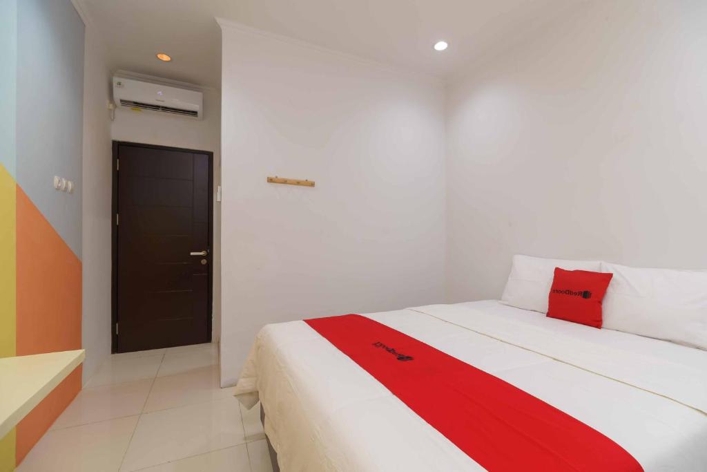 a bedroom with a bed with a red blanket on it at RedDoorz @ Taman Galaxy Bekasi in Cikunir Satu