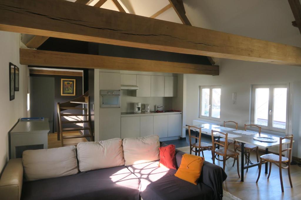 a living room with a couch and a kitchen and a table at B&B / Studio De Druivelaar in hartje Kluisbergen (Berchem) in Kluisbergen