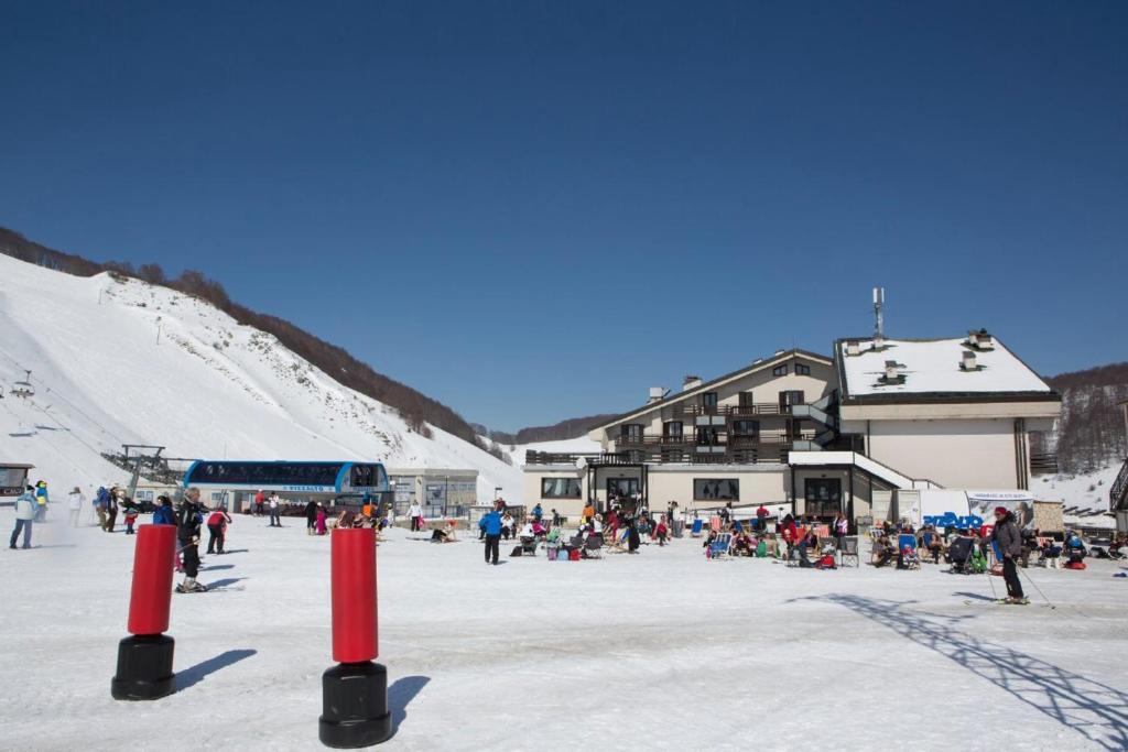 a group of people standing in the snow near a ski lodge at Hotel Pizzalto in Roccaraso