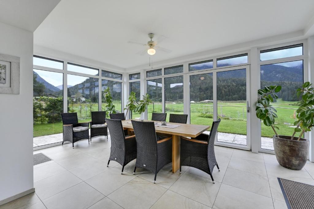 een eetkamer met een tafel, stoelen en ramen bij Ferienwohnung Panorama Eg in Inzell