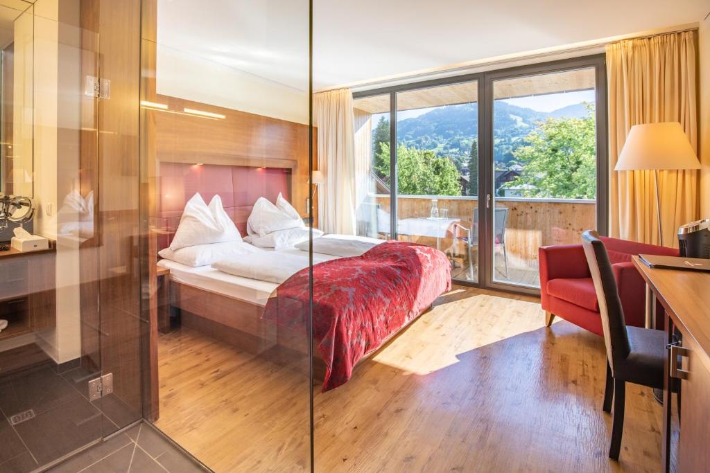 a bedroom with a bed and a large window at Sonne 1806 - Hotel am Campus Dornbirn in Dornbirn