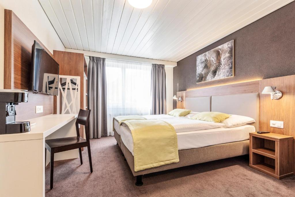 Pokój hotelowy z łóżkiem i biurkiem w obiekcie Campanile Martigny w mieście Martigny