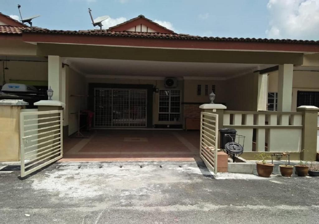 een huis met een poort en een garage bij Kayu Merbau Homestay in Seri Iskandar