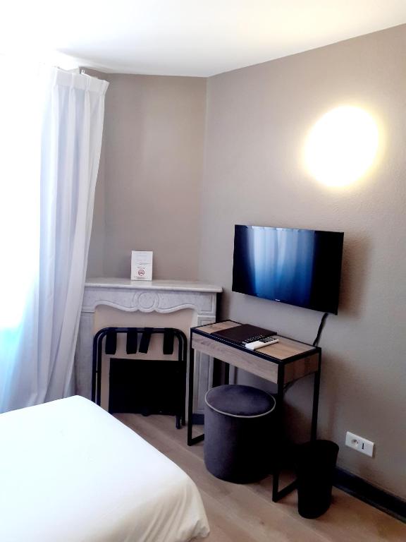 a bedroom with a bed and a desk with a television at Hôtel La Villa Tosca in Cannes