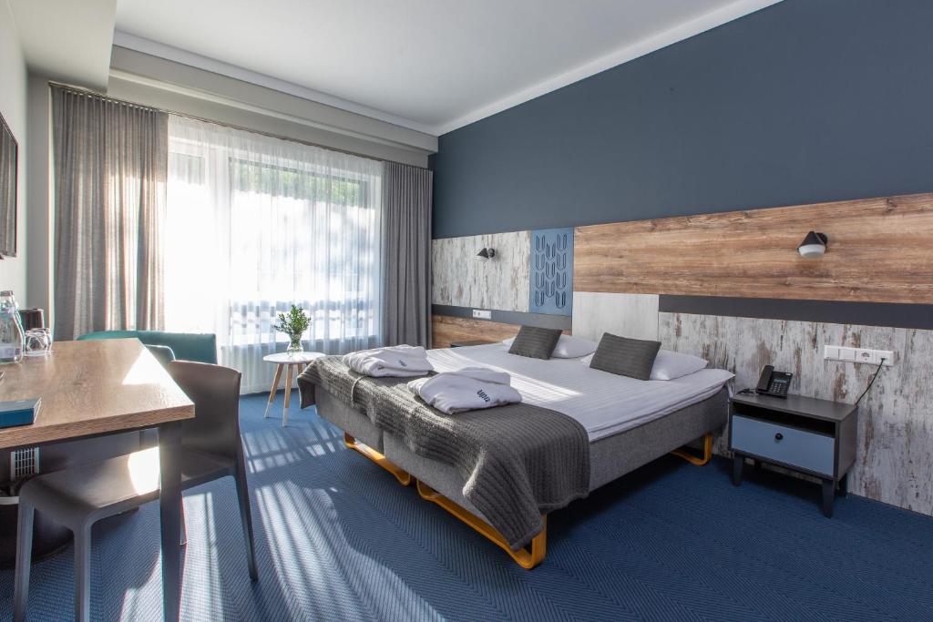 a bedroom with a large bed and a desk at UPA Medical SPA in Druskininkai