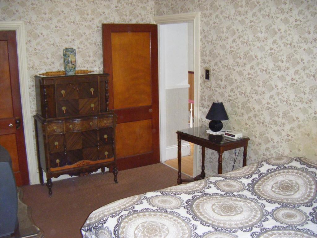 a bedroom with a bed and a dresser and a table at Auberge des Arts Bed and Breakfast in Ottawa
