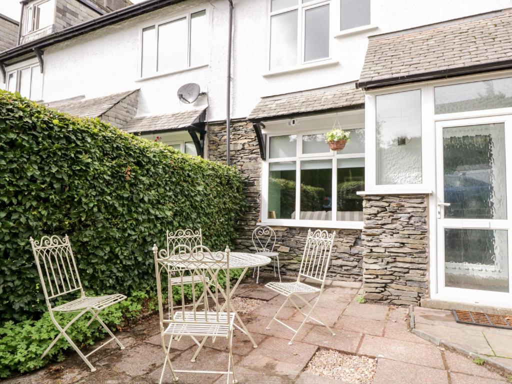 a patio with chairs and a table in front of a house at Walker's Cottage in Windermere