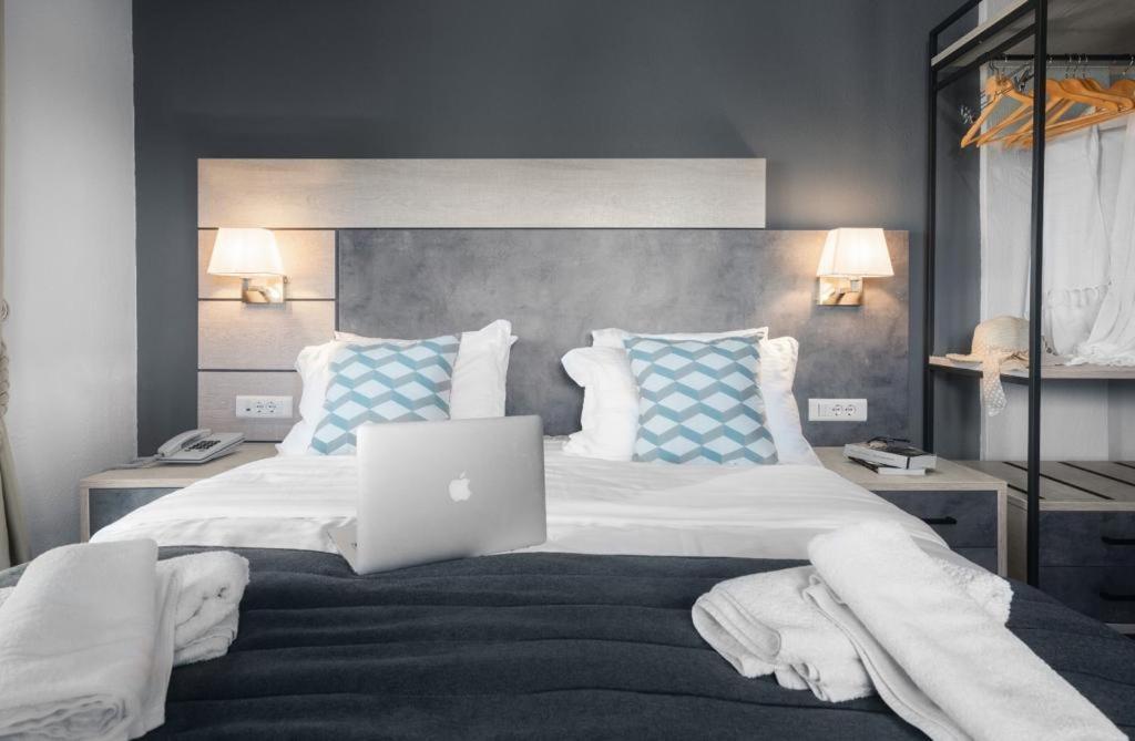 ein Schlafzimmer mit einem Bett und einem Laptop darauf in der Unterkunft Meliton Inn Hotel & Suites by the beach in Neos Marmaras