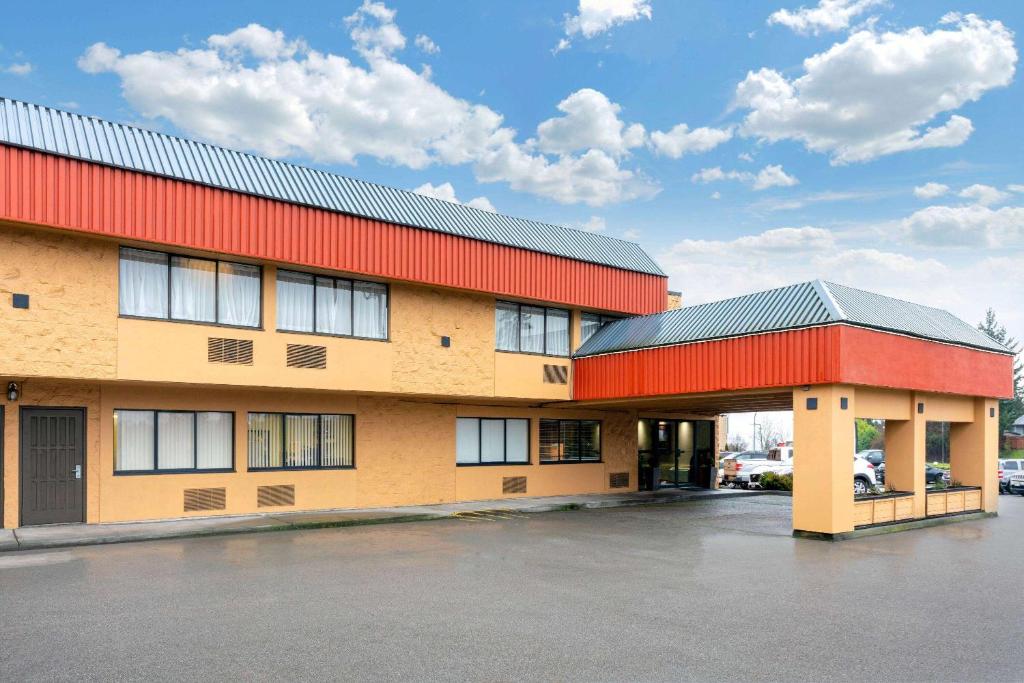 a building with a red roof and a parking lot at Ramada by Wyndham Coquitlam in Coquitlam