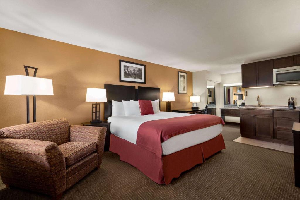 a large hotel room with a bed and a chair at Baymont by Wyndham Cortez in Cortez
