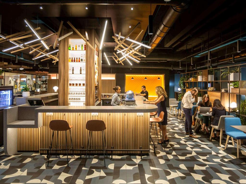 a lobby of a restaurant with people standing around a bar at Novotel Strasbourg Centre Halles in Strasbourg