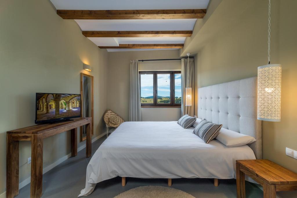 um quarto com uma grande cama branca e uma televisão em Hotel Mas De Cebrian em Puertomingalvo