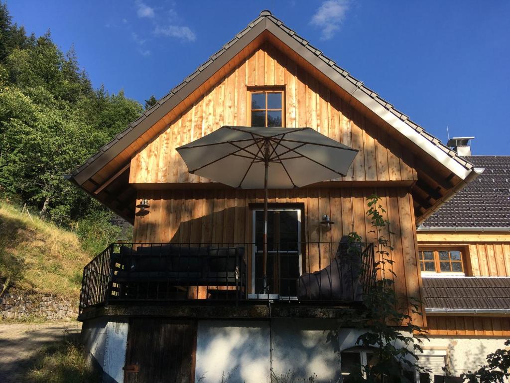 a house with a balcony with an umbrella at Ferienwohnung SichtWeiten in Seebach