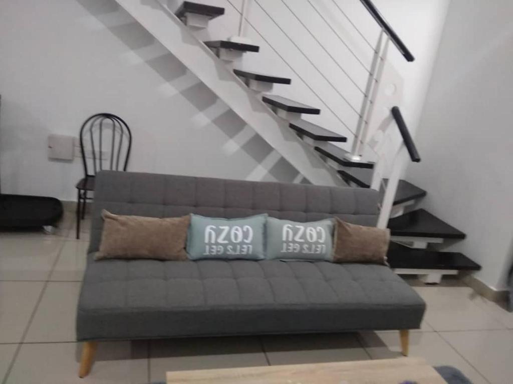 a couch with pillows in a living room with stairs at Duplex Scott Garden in Kuala Lumpur