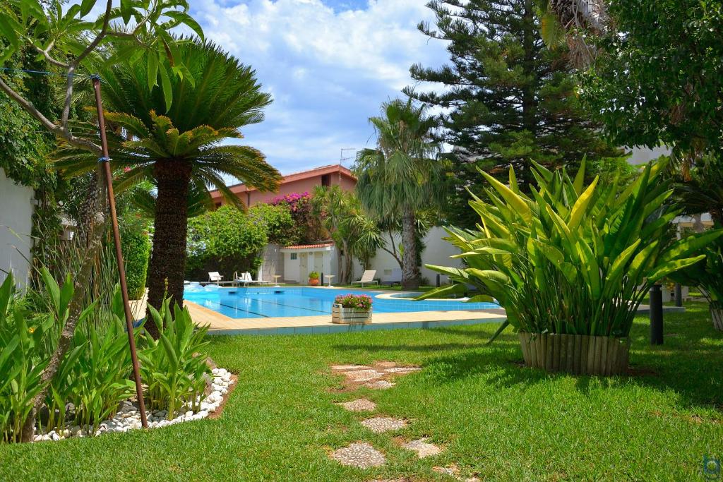 un cortile con piscina e palme di B&b Mondello Resort a Palermo