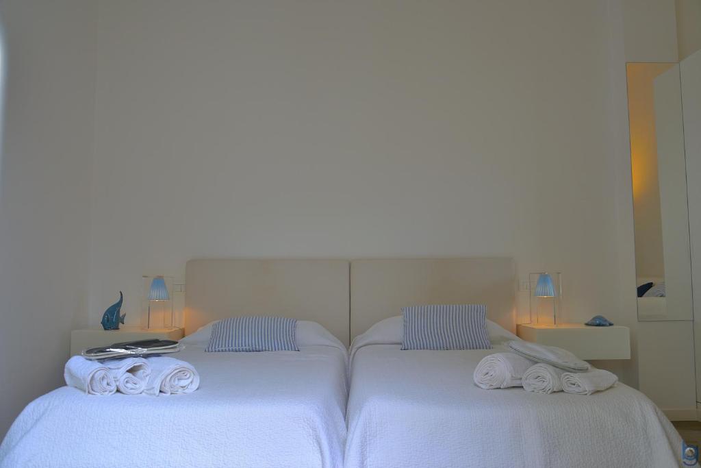 two beds in a room with white sheets and towels at B&b Mondello Resort in Palermo