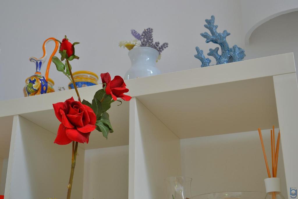 a white shelf with red roses and vases on it at B&b Mondello Resort in Palermo