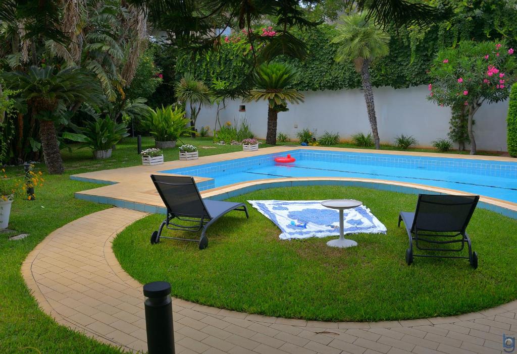 two chairs and a table next to a swimming pool at B&b Mondello Resort in Palermo