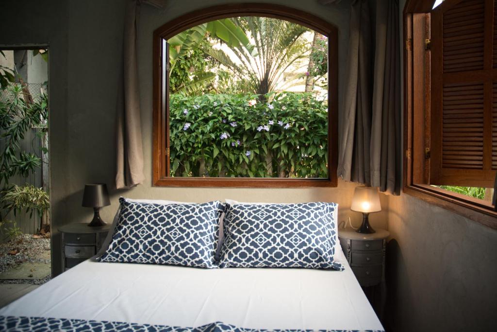 um quarto com uma cama e uma janela em Jardim Secreto Guest House em Búzios