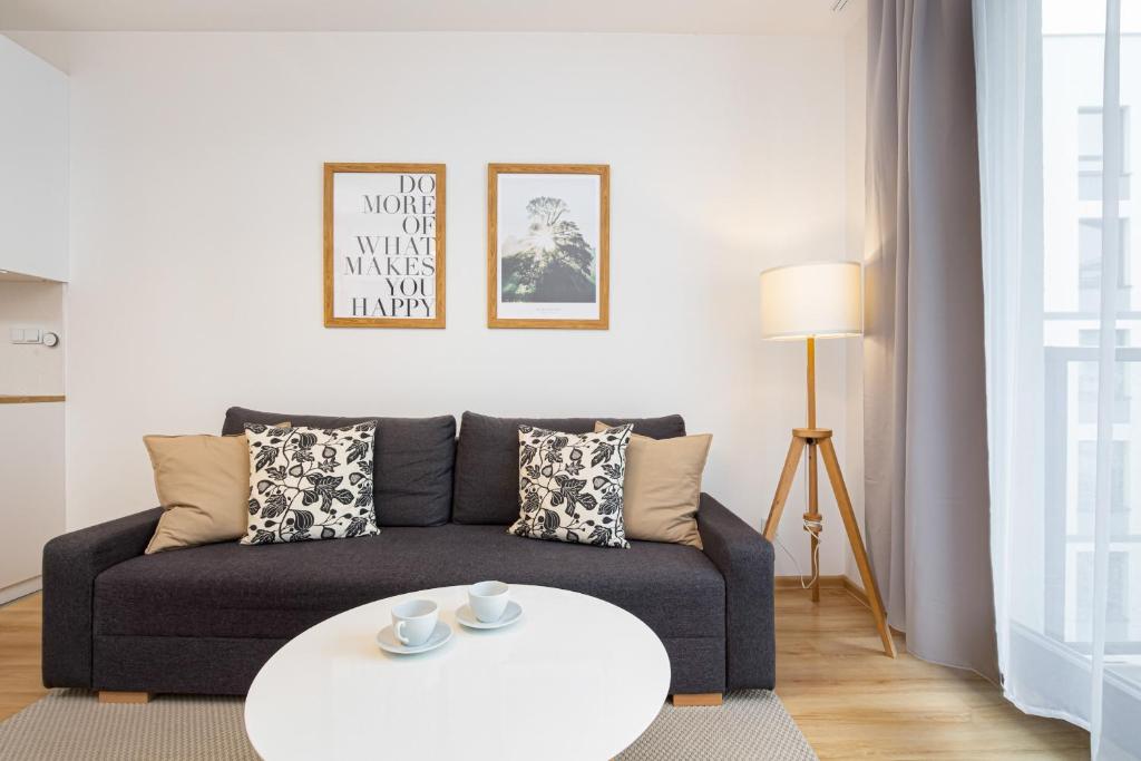 ein Wohnzimmer mit einem Sofa und einem weißen Tisch in der Unterkunft Apartments Varsovia Kasprzaka by Renters in Warschau
