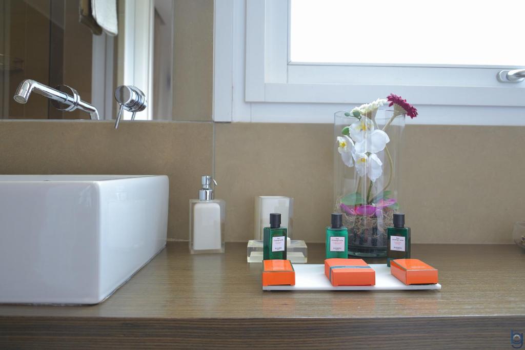 a bathroom counter with a sink and a vase of flowers at B&b Mondello Resort in Palermo