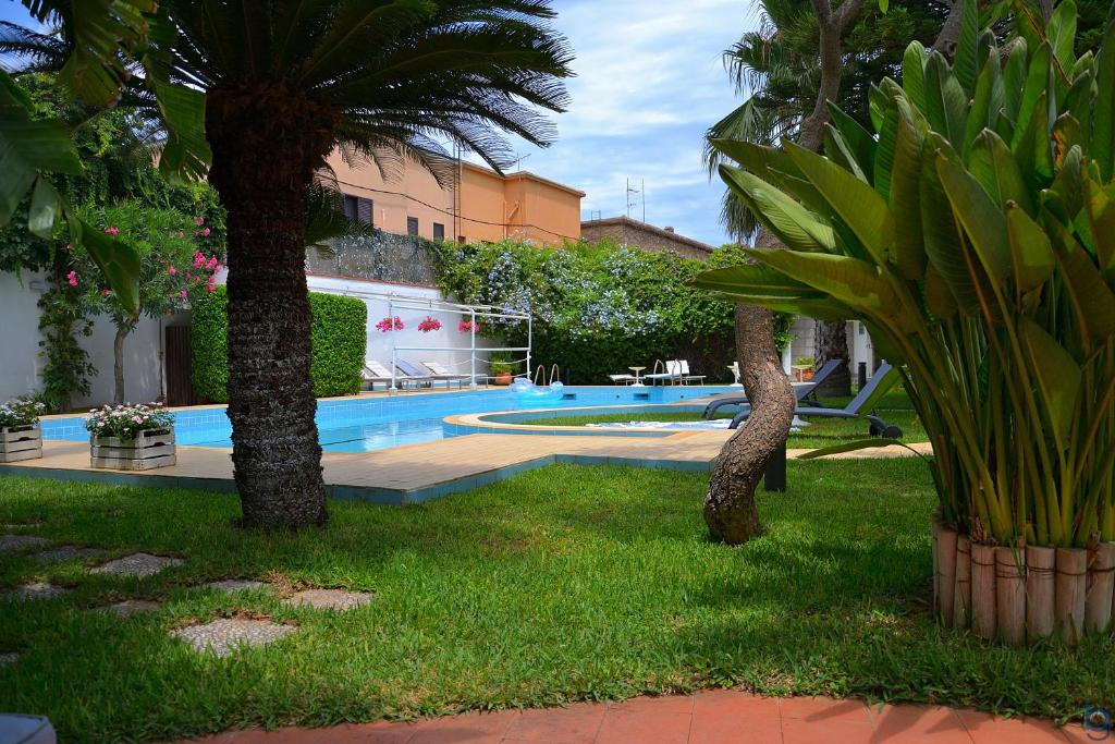 a swimming pool with two palm trees in a yard at B&b Mondello Resort in Palermo