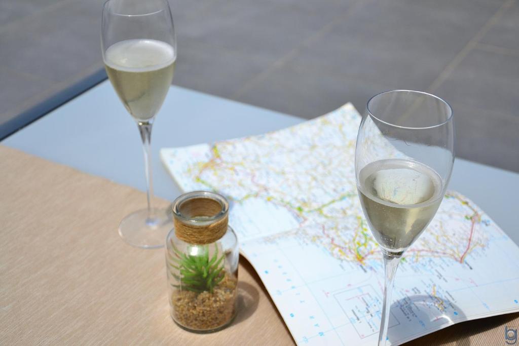 two glasses of wine sitting on a table with a map at B&b Mondello Resort in Palermo