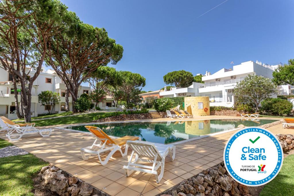 a pool with chairs and a sign that says clean and safe at Fresh Sunny Flat with Pool & Terrace by Host Wise in Albufeira