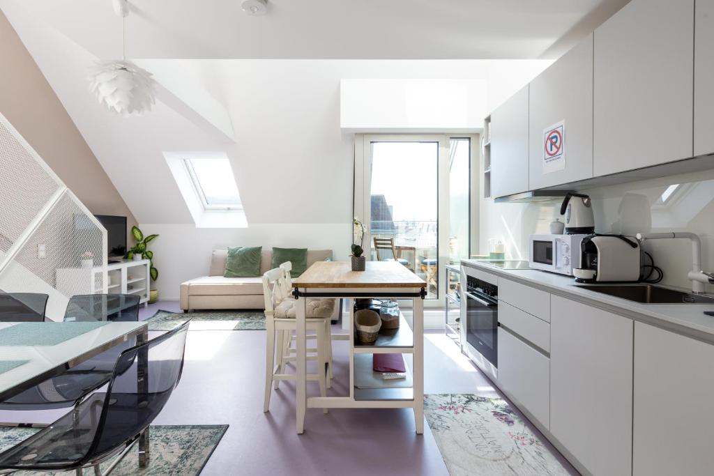 una cocina con armarios blancos y una mesa en una habitación en JULIUS 28 - Duplex apartment 5 mins to city center, en Viena