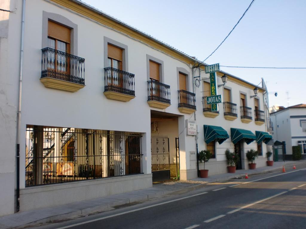 biały budynek z balkonami przy ulicy miejskiej w obiekcie Hostal las Tres Jotas w mieście Alcaracejos