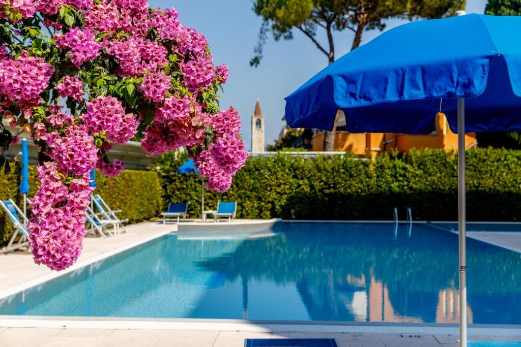 a swimming pool with pink flowers and an umbrella at Hotel Idania in Bardolino