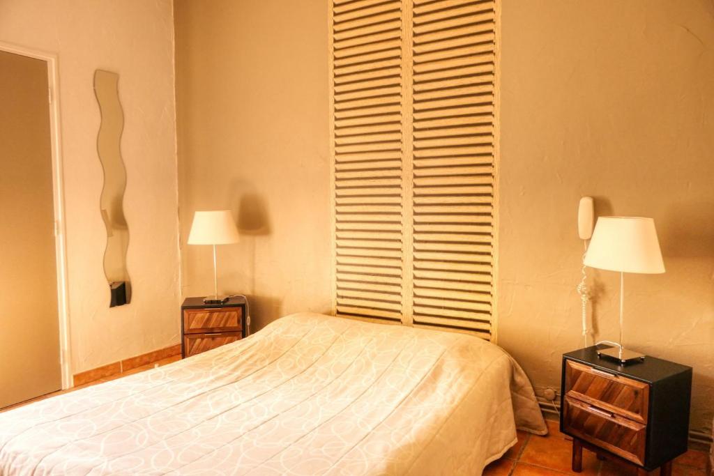 a bedroom with a bed and two lamps and a window at Au Saint Roch - Hôtel et Jardin in Avignon