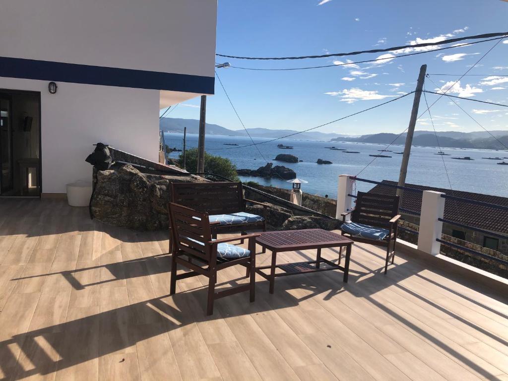 balcón con 2 sillas, mesa y vistas al océano en Camarote de la Villa, en Bueu