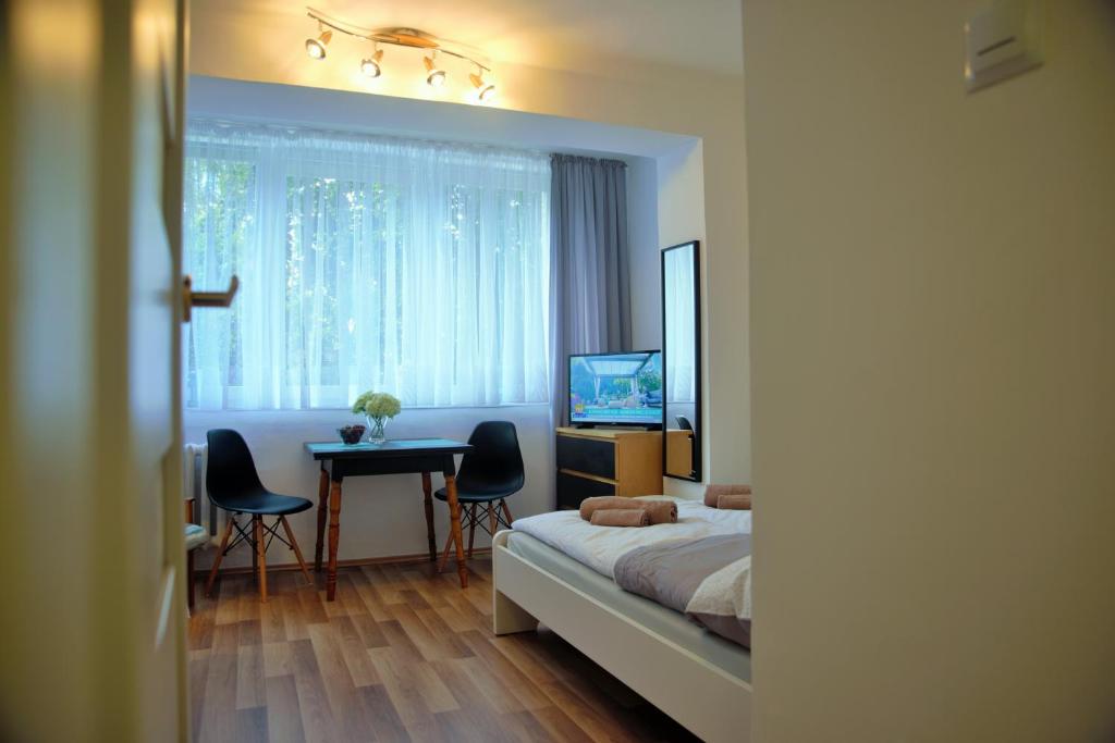 a bedroom with a bed and a table and a television at Friendly Place Doki in Gdańsk