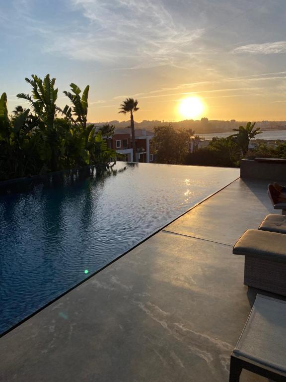 una piscina con puesta de sol en el fondo en VILLA BEAU, en Ferragudo