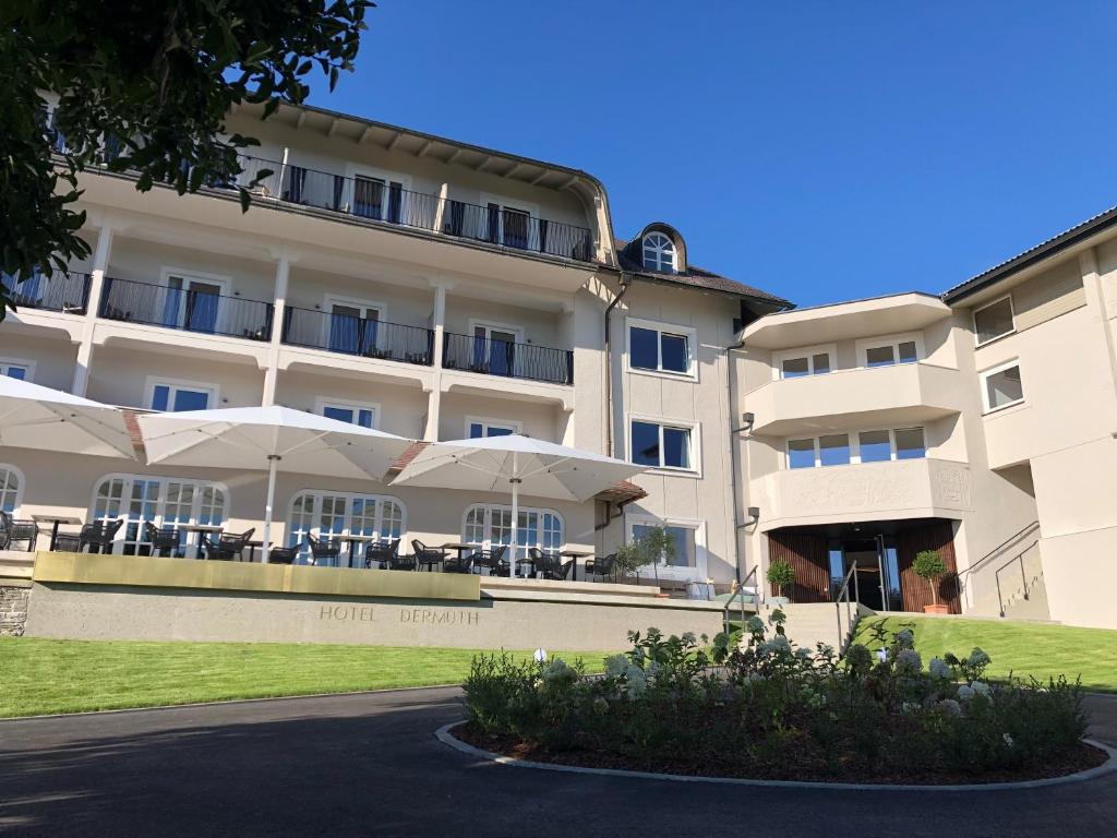 a hotel with tables and umbrellas in front of it at Hotel Dermuth Klagenfurt in Klagenfurt