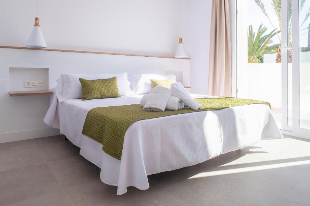 a white bed with a green blanket and pillows on it at Hotel Senderos in Agua Amarga