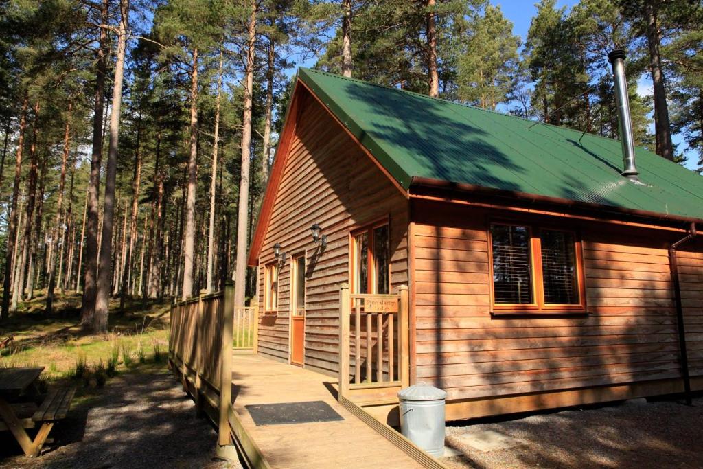 une petite cabane en bois avec un toit vert dans l'établissement Cairngorm Lodges, à Aboyne