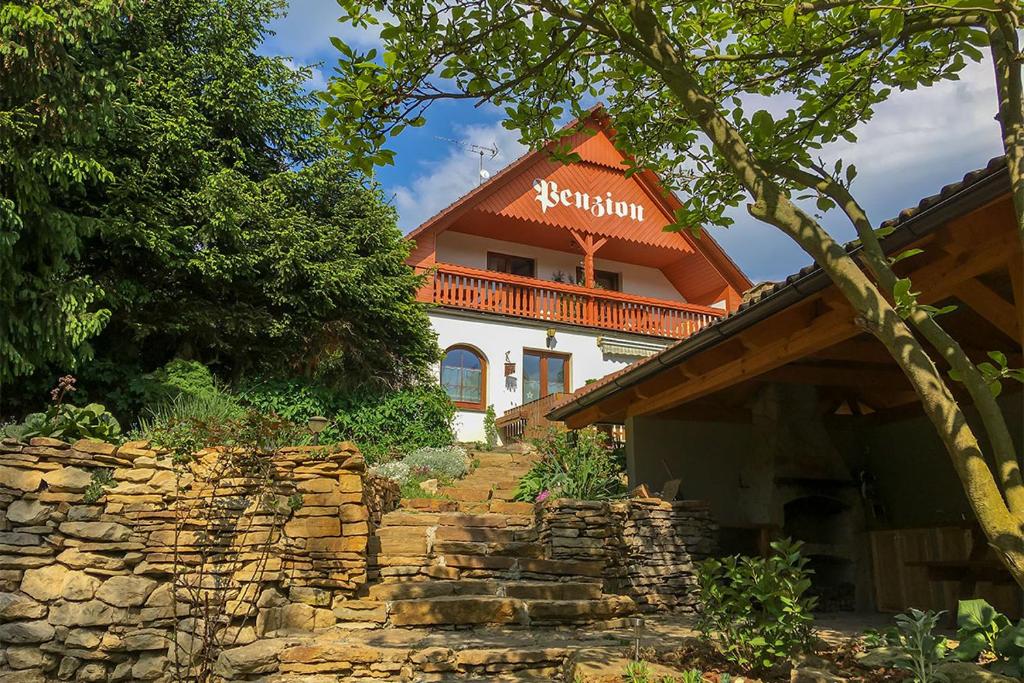 ein Haus mit einem orangenen Dach und einer Steinmauer in der Unterkunft Penzion Na Hradčanech in Neustadt an der Mettau