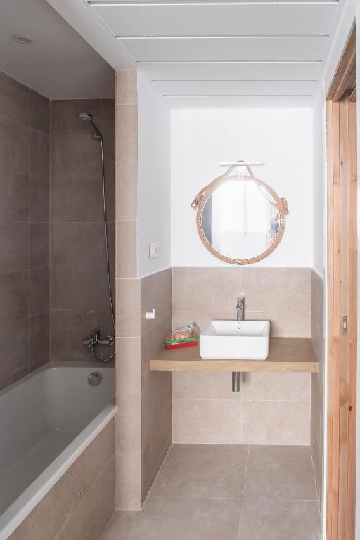 a bathroom with a sink and a tub and a mirror at Hotel Senderos in Agua Amarga